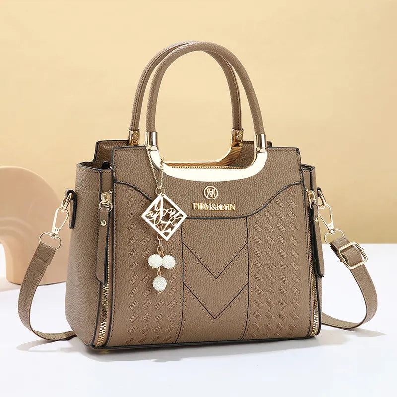 Bolso bandolera para mujer con costuras en forma de V, herrajes dorados, múltiples compartimentos y asa superior.